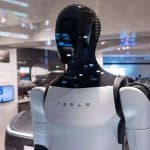 Robô Tesla com design futurista e corpo humanoide apresentado em espaço tecnológico, simbolizando inovação em automação e inteligência artificial.