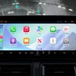 Tela de carro com Apple CarPlay exibindo aplicativos de música, mapas, mensagens e assistentes de IA de terceiros integrados para uma experiência de condução inteligente.